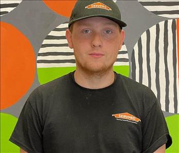 ethan (man) standing in front of green and orange mural background