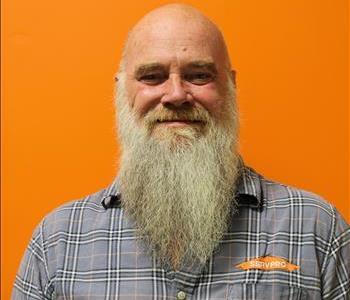 A man in a plaid shirt standing in front of an orange background