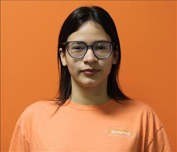 A woman in an orange shirt standing in front of an orange background