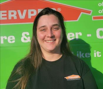 Khristinas a womAn standing in front of a green servpro van as the back drop