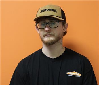 A man in a black shirt standing in front of an orange background