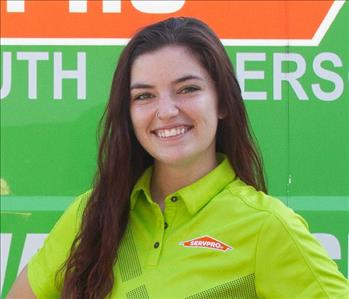 Elise a women, standing in front of a green SERVPRO van