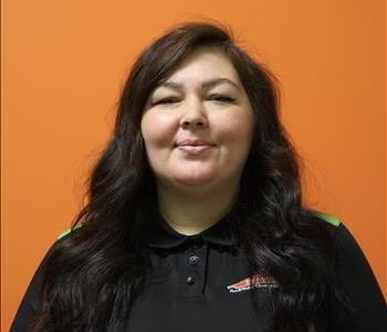 A woman in a black shirt standing in front of an orange background