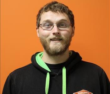 A man in a black hoodie standing in front of an orange background