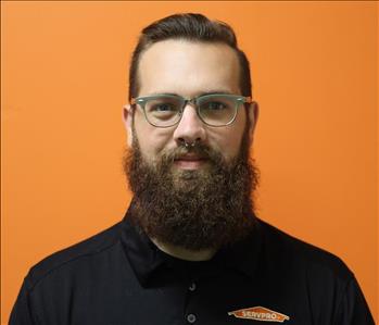 A man in a black shirt standing in front of an orange background