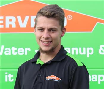 Josh a man standing in front of a green servpro van as the back drop 
