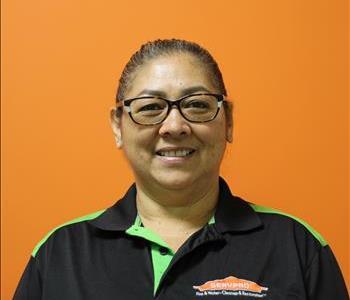 A woman in a black shirt standing in front of an orange background